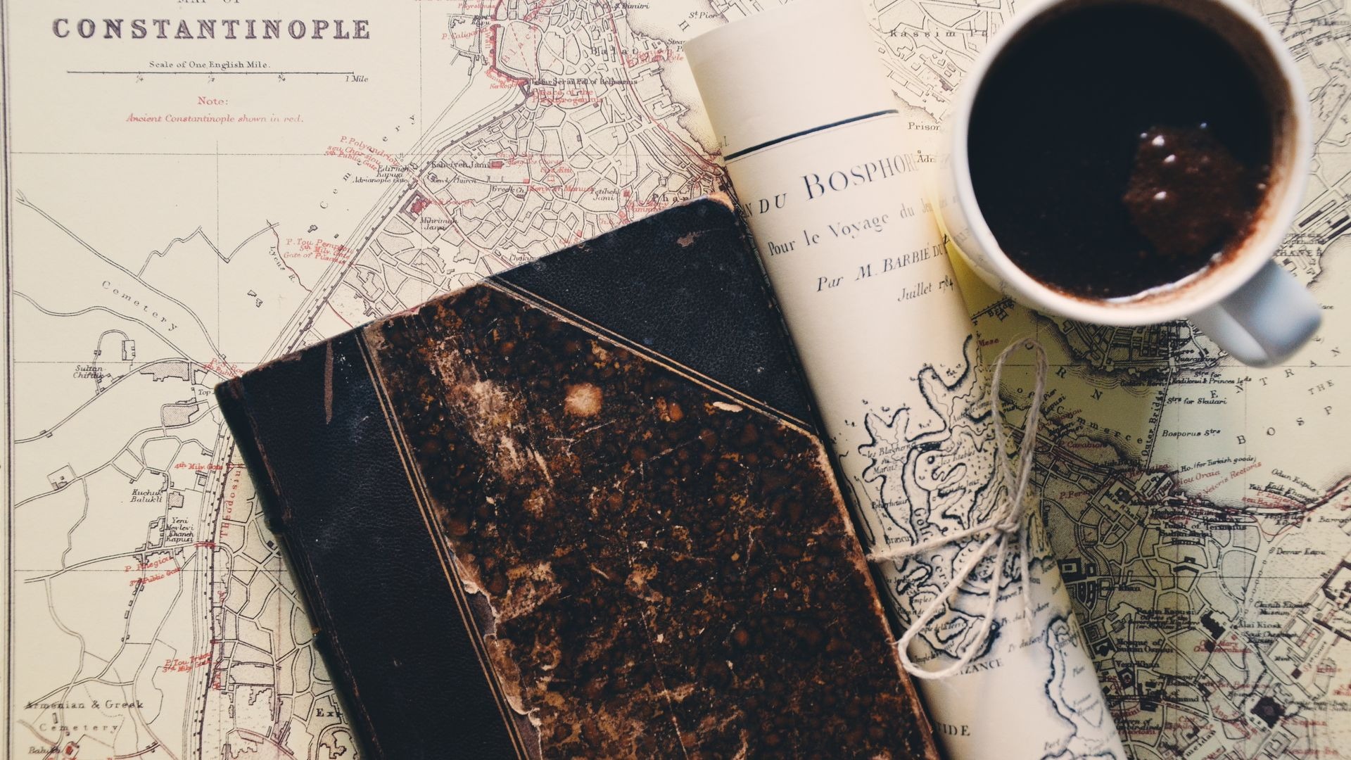 Mapa antiguo, libreta de viaje y una taza de café sobre un escritorio