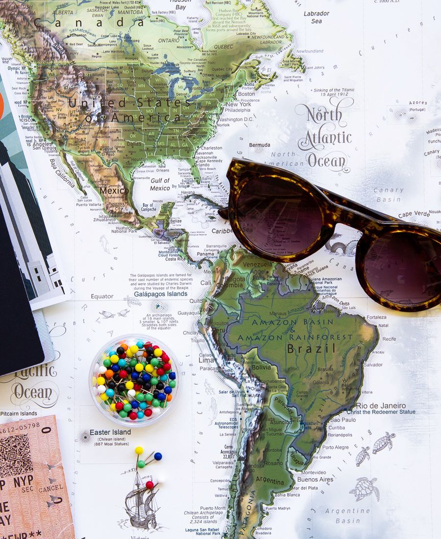 Pasaporte, lentes de sol y una postal sobre un mapa del mundo